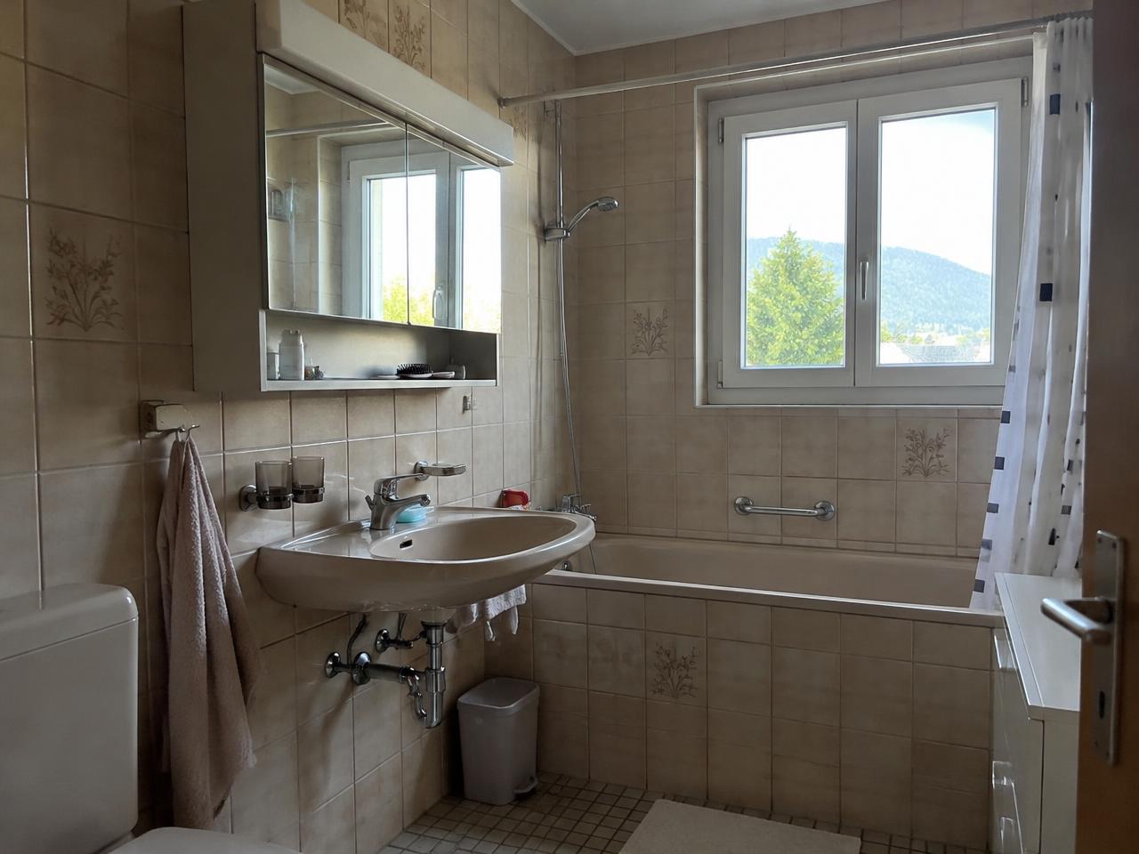 Altes Lavabo mit Spiegelschrank und Badewanne in einem Schweizer Bad vor der Renovation